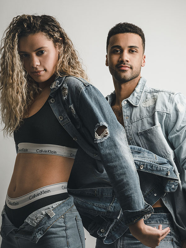 Two people dressed in Jean material with a jacket being flipped towards right side of the frame.