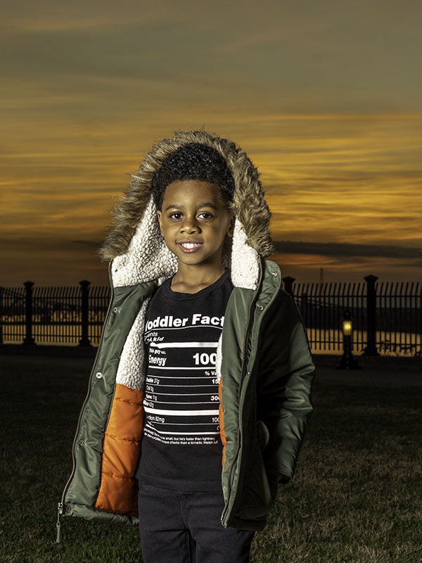 outdoor portrait of young boy with jacket against colorful sunset