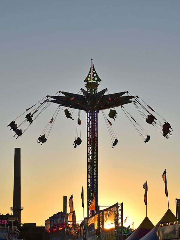 Minnesota State Fair midway at sundown, people riding giant swings