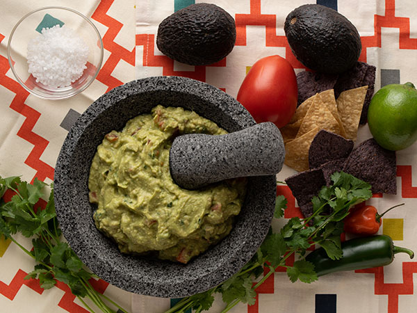 Guacamole in bowl with raw ingredients on the right side