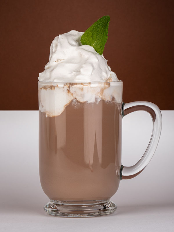Hot chocolate in clear glass with whipped cream and mint