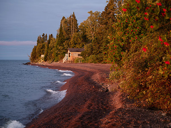 Boat house on shore of Lake Superior with trees on the right