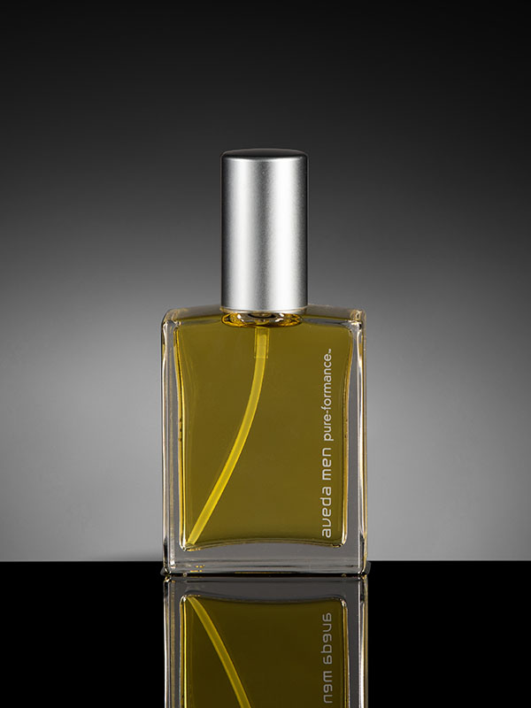 Bottle of cologne on black table with grey background